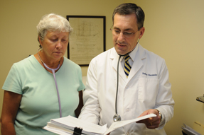 Rodney Hornbake FACP right and medical assistant Martha Lapman review charts at his practice Dr Hornbake returned to medical practice after spending years in administration at a for-profit compa